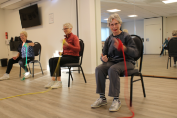 Vrouwen die een oefening doen op een stoel met een gekleurd touw