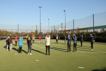 Groep met mensen die in een kring staan en rekoefeningen doen