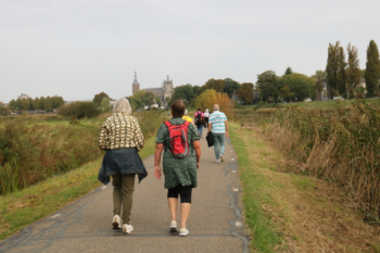 Mensen wandelend gefotografeerd via de achterkant, op de achtergrond de sint jan