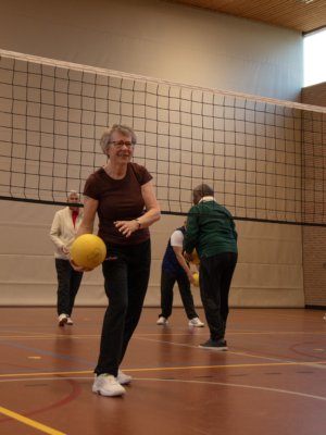 Een vrouw met een gele bal die de bal overspeelt