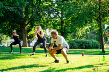 Sportende mensen op een grasveld die squad bewegingen doen