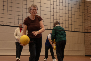 Een vrouw met een gele bal die de bal overspeelt