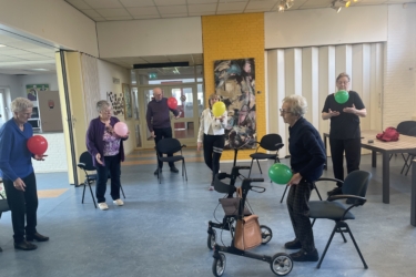 Deelnemers die staan in de zaal en die een gekleurde ballon vasthouden