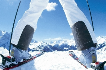 Twee benen die op skilatten staan met bergen als achtergrond