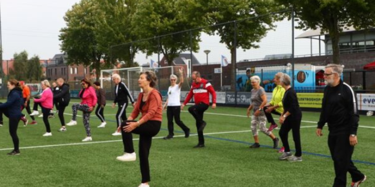 Groep oudere mensen die meedoen aan een buitenles op een grasveld