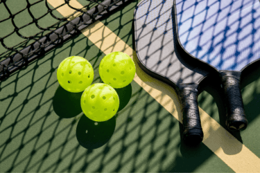 Een pickleball paddle die op de grond ligt met pickballen erbij