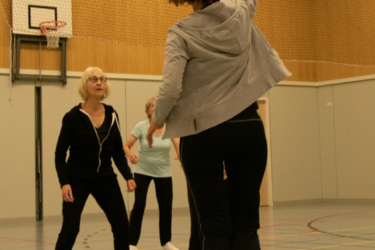 Sportende vrouw in een gymzaal speelt de bal over het volleybalnet.